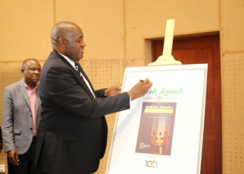 Hon. Chris Baryomunsi signs a dummy of the Book "Academics, Research and Leadership in Institutions of Higher Learning: Experiences from Makerere University" signifying its launch on 29th July 2022.