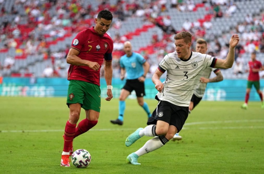 MUNICH, GERMANY - JUNE 19: Cristiano Ronaldo of Portugal runs with the ball whilst under pressure from Marcel Halstenberg of Germany during the UEFA Euro 2020 Championship Group F match between Portugal and Germany at Football Arena Munich on June 19, 2021 in Munich, Germany. (Photo by Matthias Schrader - Pool/Getty Images)