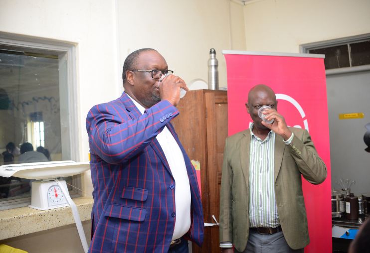 Absa Managing Director Mumba Kalifungwa, and Fort Portal Regional Referral Hospital Deputy Director Dr Oscar Kaliisa taste the water from one of the dispensers (PHOTO/Courtesy)