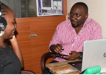Sir Khoi Koi testing his app with a cliet at his office in Mbarara City