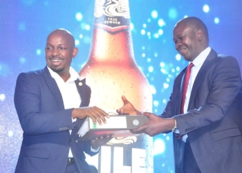 Onapito (R) hands over to Mr Emmanuel Njuki as the new head of legal and cooporate affairs at Nile Breweries Limited