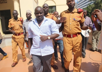 Sebuufu (in short sleeves) being led to court cells during High court trial.