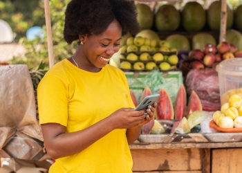 Wesotinge with MTN MoMo: Market Vendor accessing the MTN MoMo Loans and Savings on her phone