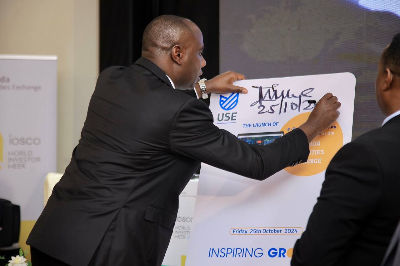Uganda's Minister of State for Finance, Planning, and Economic Development, Henry Musasizi, signs the launch of the Uganda Securities Exchange's e-platform for Treasury bills and bonds
