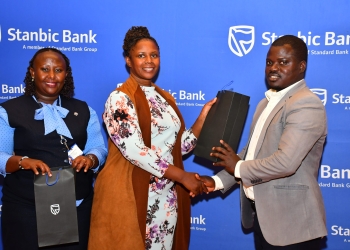 Sylvia Atuhairwe (C), the Stanbic Head of Distribution handing over a gift to one of the SACCO leaders.