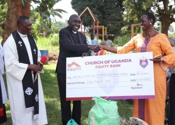 Rev. Canon Captain William Ongeng handing over a dummy cheque to Mrs. Joy Mwesigye, the Director of Kampala School for the handicapped in Mengo on Sunday.
