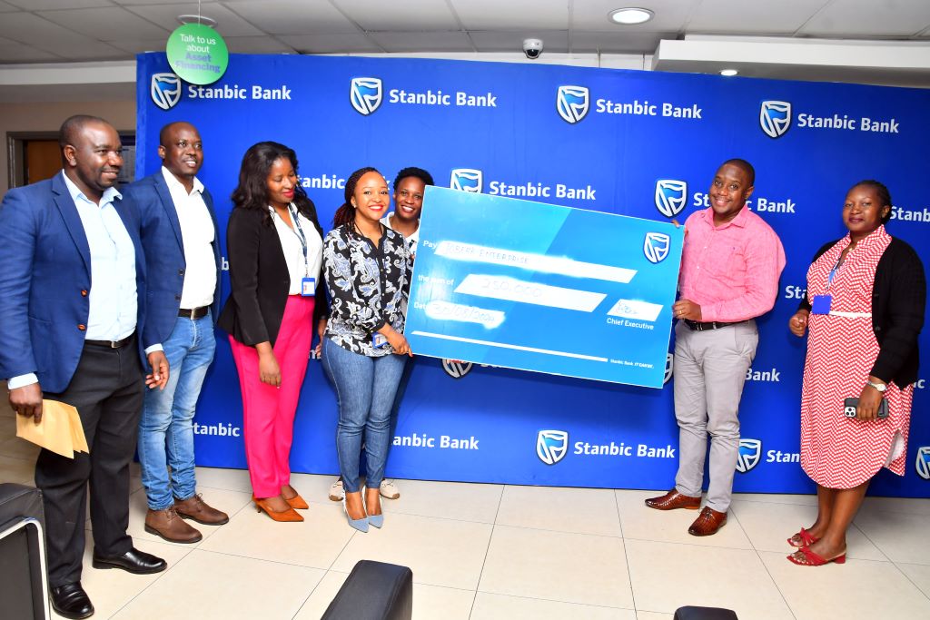 Stanbic Bank Officials led by Tito Ssaka (1L), the Eastern Region Head Agent Banking, hand over a dummy cheque to the Managing Director of Joberk Enterprises.