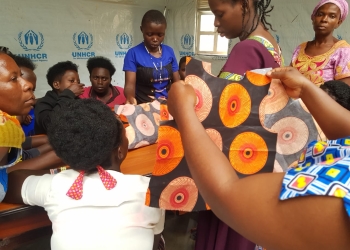Beneficiaries from Kakoni Women and girls Safe space showing some of their work as others continue to practice tailoring skills.