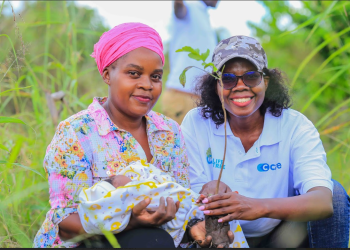 Sheila Aboth,(R),Head Of Brand and Client Experience C Care, joins in the tree planting ceremony with one of the parents