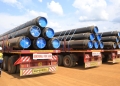 Workers offload part of the East African Crude Oil Pipeline. The project includes advanced monitoring systems for safety.