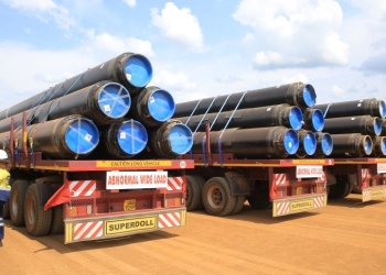 Workers offload part of the East African Crude Oil Pipeline. The project includes advanced monitoring systems for safety.