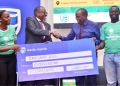 Baziwe Alan, the Stanbic Vice President Public sector handing over the dummy Cheque to Issa Katwesigye, Ast Commissioner for Forestry in the Ministry of Water and Environment, Looking on is Stanbic's Catherine Asay