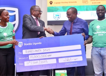 Baziwe Alan, the Stanbic Vice President Public sector handing over the dummy Cheque to Issa Katwesigye, Ast Commissioner for Forestry in the Ministry of Water and Environment, Looking on is Stanbic's Catherine Asay