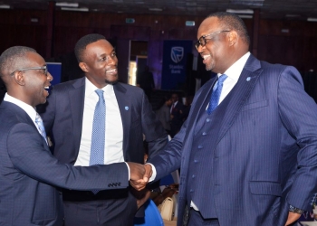 Mumba Kalifungwa (R), Stanbic Bank Chief Executive shaking hands with Ronald Makata, bank's Chief Finance Officer, Looking on is Tich Makonese, the Stanbic Head Bankassurance