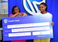 Sarah Nankumba, the Stanbic Acacia branch manager handing over a dummy cheque to Akugizibwe Annet Mbabazi, One of the lucky winners in the kyadouble with Supa Dupa campaign