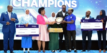 Sarah Kagingo, the Vice Board Chairperson of Private Sector Foundation handing a shield of excellence to Sumaya Girls patron teacher.