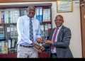 Dr. ......, Executive Director of TASO receiving an accolade from Dr. Bildard Baguma, Executive Director JMS on Thursday.