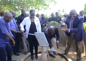 Sheila Sabune, the Corporate Relations Director and Hon.Okasai Opolot operate the borehole as Jimmy Biyomotho , Ministry of Water and Environment Regional Manager (in necktie) washes his hands