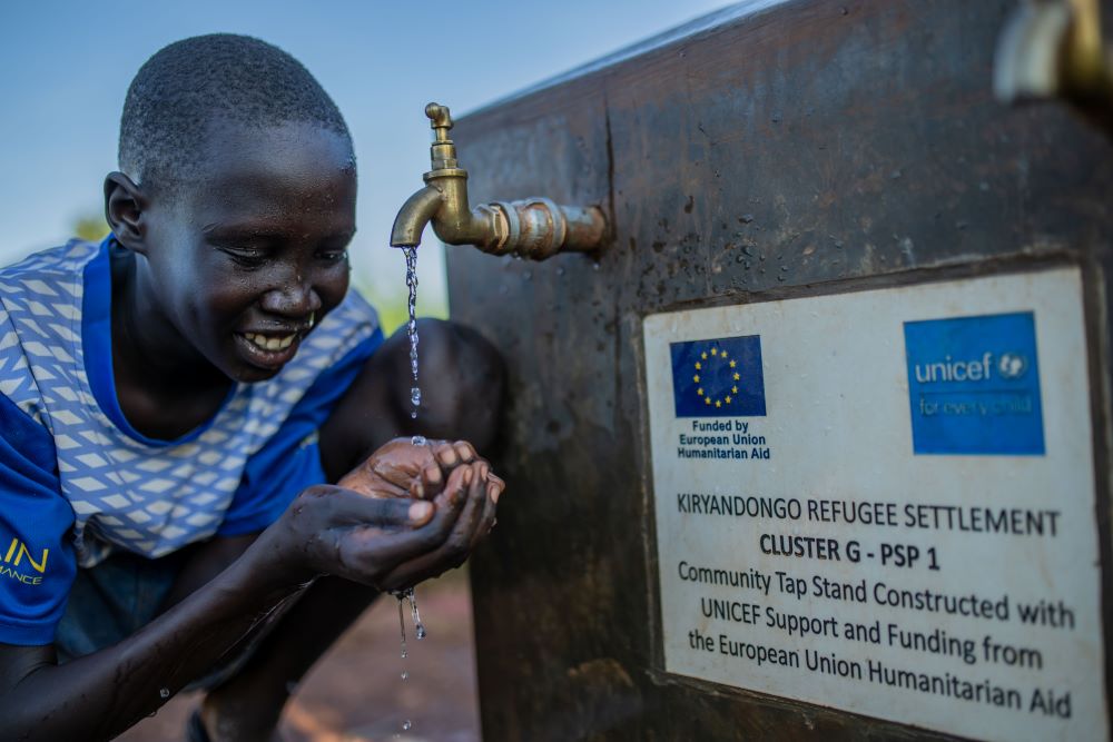 Eleven-year-old Laul Marol drinks clean water from a tap stand in Cluster I, Kiryandongo Refugee Settlement, on October 14, 2025. The facility was installed by UNICEF with support from European Union Humanitarian Aid. Throughout the settlement, children like Marol are drawn to the sound of flowing water. They gather at the tap stands to drink, rinse their faces, and wash away the day's dust from their legs, their laughter filling the air. These everyday moments of childhood made possible by reliable access to safe water, represent a fundamental shift in daily life across the camp. © UNICEF/UNI881276/Bamulanzeki