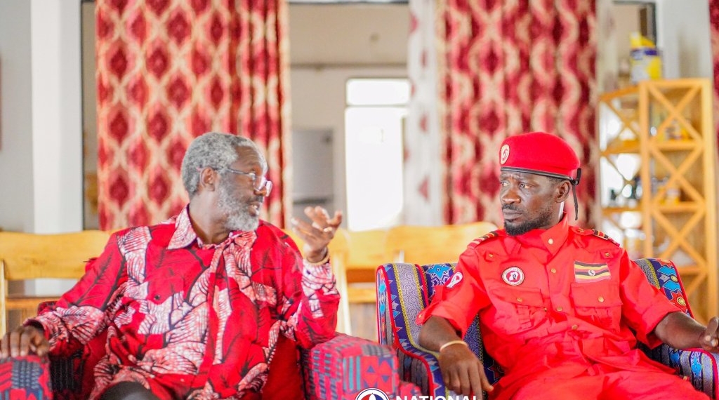 National Unity Platform president Robert Kyagulanyi, left, known as Bobi Wine, lays a national flag on the grave of former President Milton Obote as Jimmy Akena, Obote's son, looks on in Apac District, Uganda. The visit sparked debate about historical divisions.