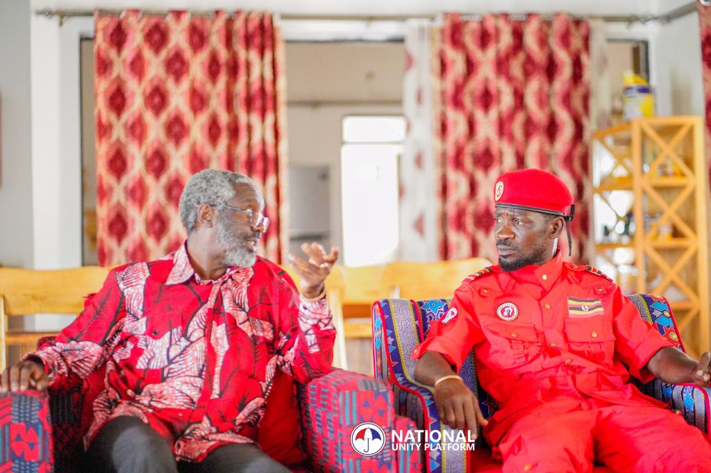 Президент Платформы национального единства Роберт Кьягуланьи (слева), известный как Боби Вайн, возлагает национальный флаг на могилу бывшего президента Милтона Оботе, а Джимми Акена, сын Оботе, наблюдает за этим в округе Апак, Уганда. Визит вызвал споры об исторических разногласиях.