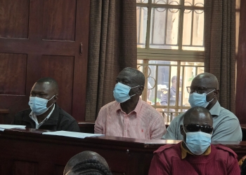 From left, Capt. Denish Oola Oyaa, retired Col. Kizza Besigye and Hajji Obeid Lutale stand in the dock at the Criminal Division of the High Court on Tuesday. (Photo by Henry Jjemba)