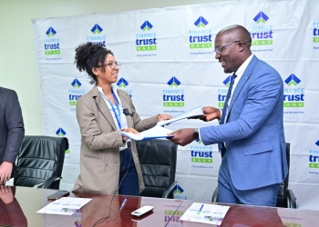 Percy Lubega, head of marketing at Finance Trust Bank, exchanges the signed partnership documents with Barbara Adolehoume, program manager for the I&P Women in Entrepreneurship for Africa program, in Kampala.