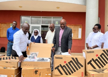 Roger Mugisha, corporate affairs lead at Letshego Uganda, left, unpacks one of 15 high-tech computers donated to University of Saint Joseph Mbarara. The equipment was received by the Rev. Deus Karemiire, vice chancellor, marking the fulfillment of a pledge made during the university’s fifth graduation ceremony in December 2025.
